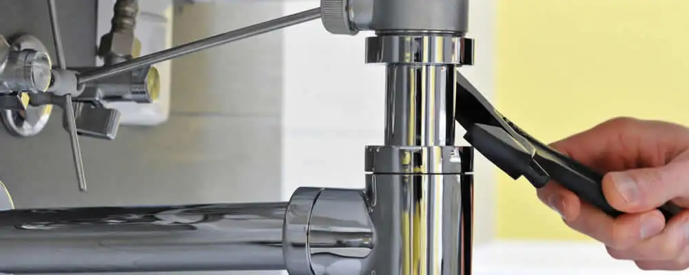 Plumber tightening a kitchen sink drain pipe connection in Hoboken, NJ
