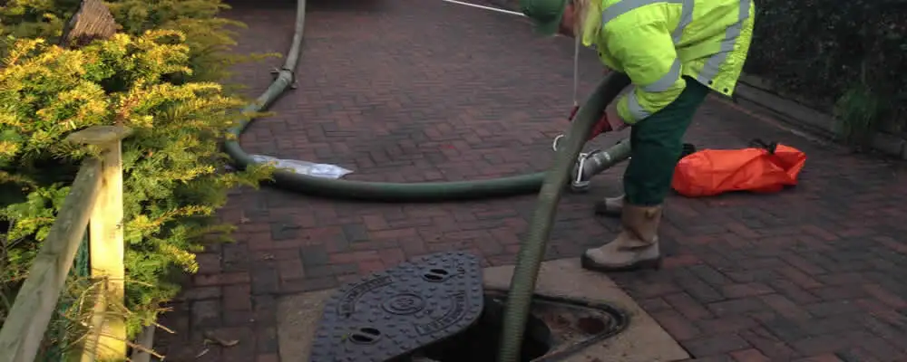 Septic tank cleaning technician servicing a septic tank with a vacuum hose in Hoboken, NJ