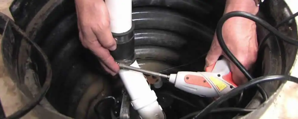 Sump pump installation technician connecting PVC discharge piping in Hoboken, NJ