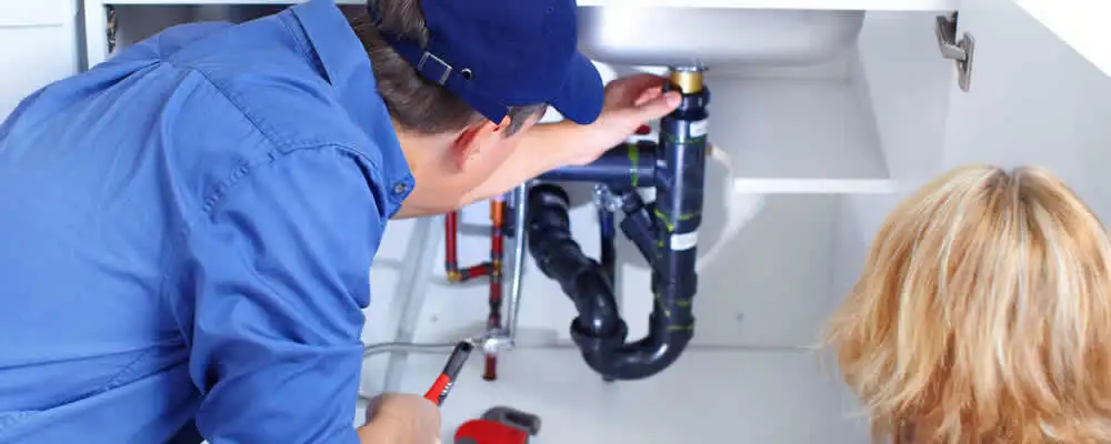 Plumber repairing under-sink drain pipes and fittings in Hoboken, NJ