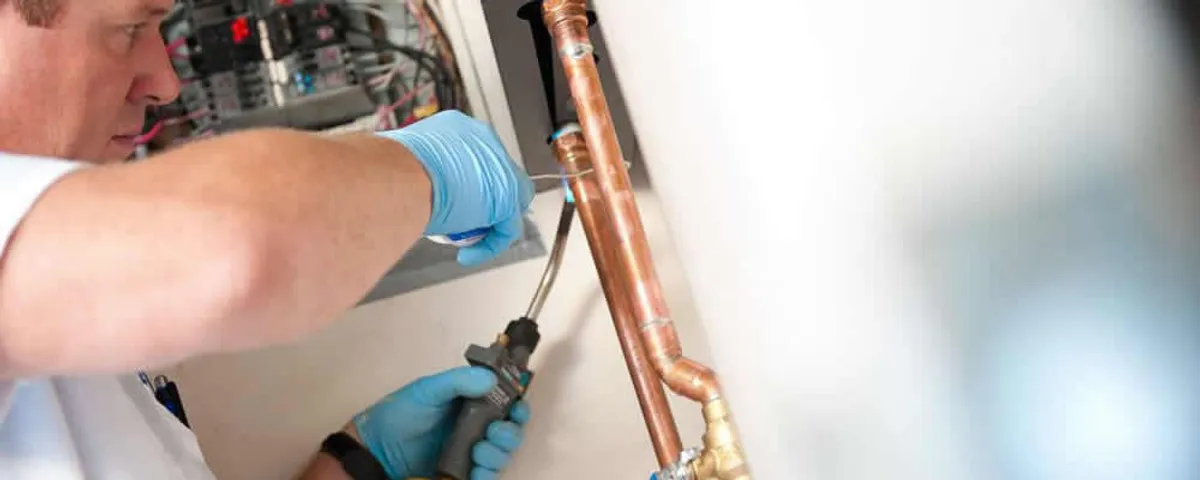 Water heater repair technician testing copper pipe connections and controls in Hoboken, NJ